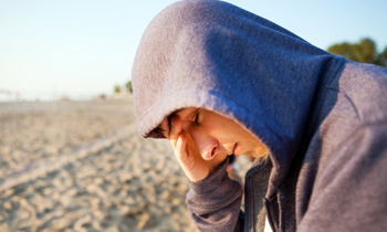 Young man in hoodie alone at beach