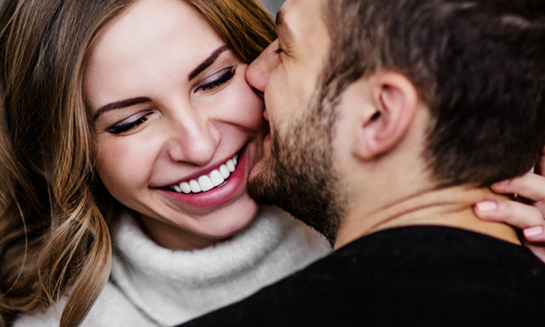 Man kissing smiling woman
