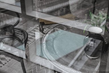 Monochrome image of a glass table and chairs reflected in a window, depicting a psychotherapy approach