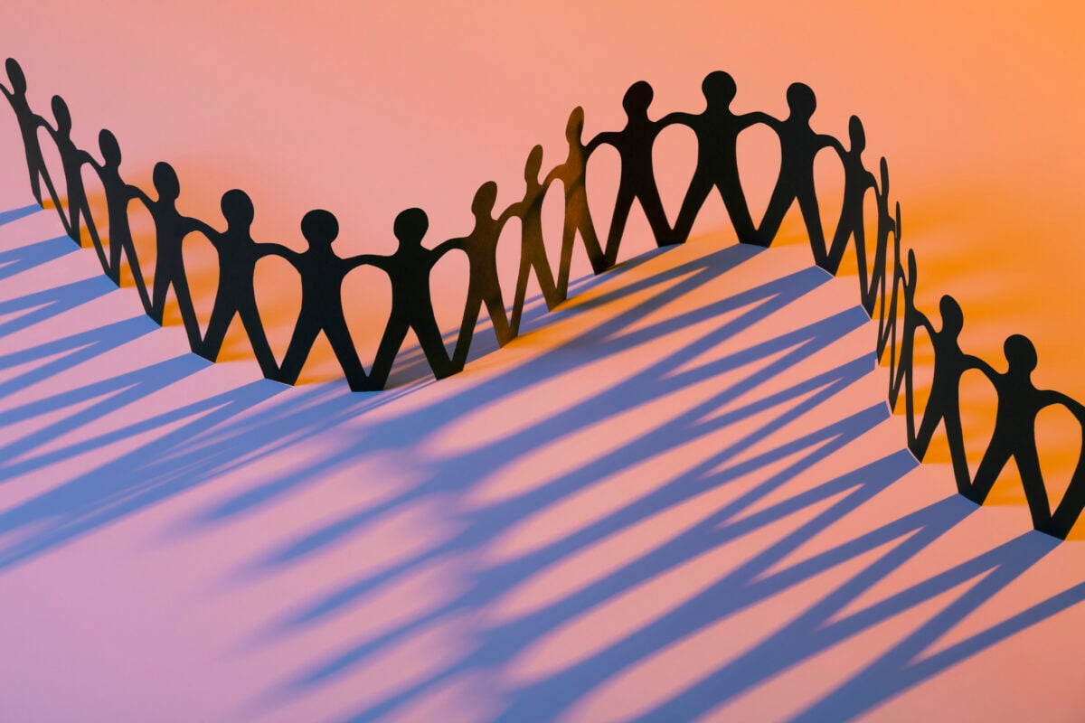 Paper chain cutout of people holding hands, symbolizing unity and family.
