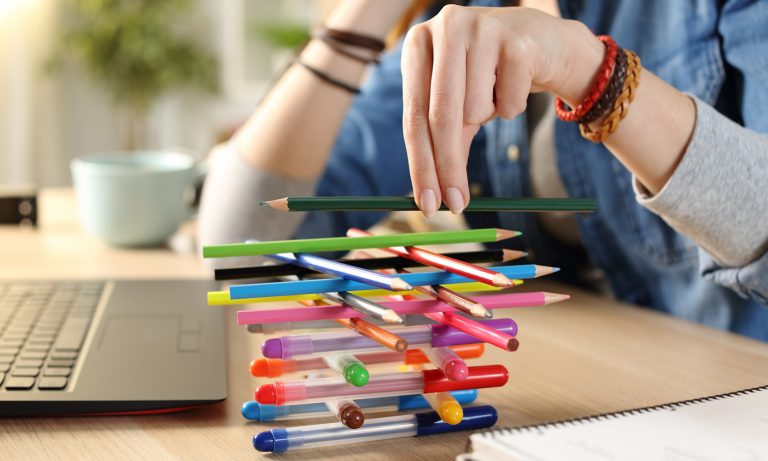 Girl sits at her desk stacking pens