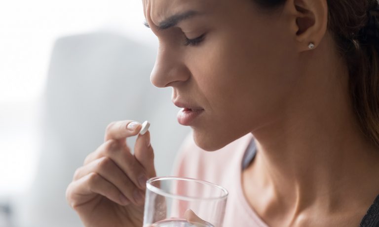Closeup of woman taking pill to mouth