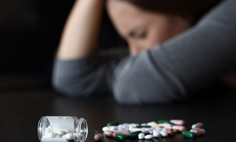 Depresija moteris šalia daug tablečių