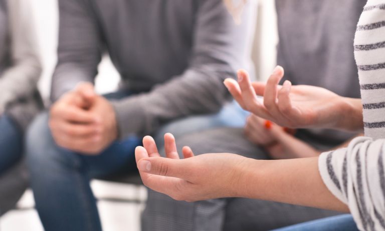 A woman's hands gesturing within an encircling support group
