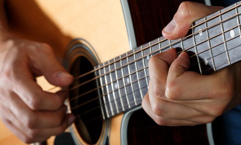 Closeup of man's hands playing acoustic guitar