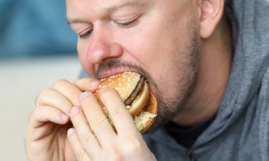 Man sitting on sofa and eating burger