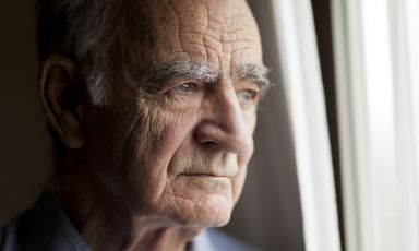 Elderly man gazing out window lost in thought