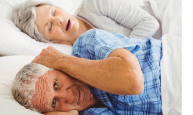 Man covering his ears, while wife is snoring