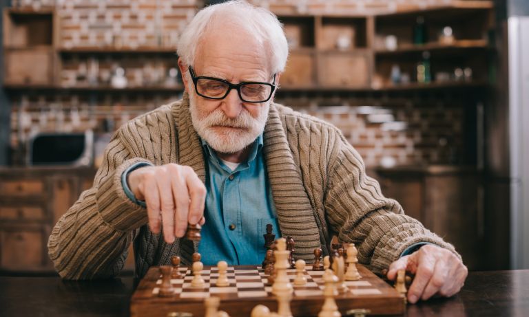 Elderly man at chess table, contemplating his next move