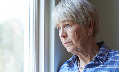 Depressed senior woman staring out of the window