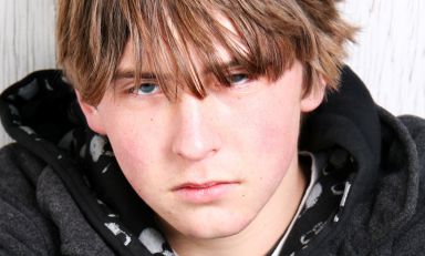 Closeup of teenaged boy appearing zoned out, his face devoid of affect