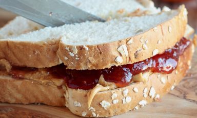 Woman's hand cutting peanut butter and jelly sandwich