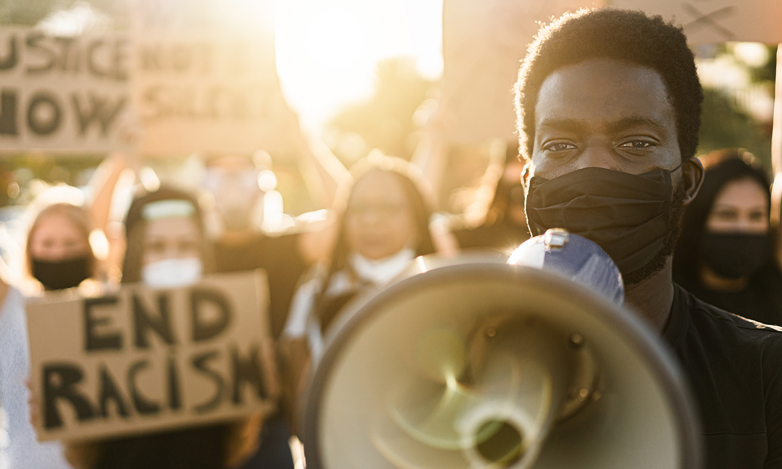 Young black man, at head of protest group, holds megaphone to his mouth