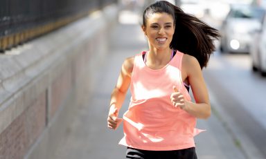 Young woman running along sidewalk